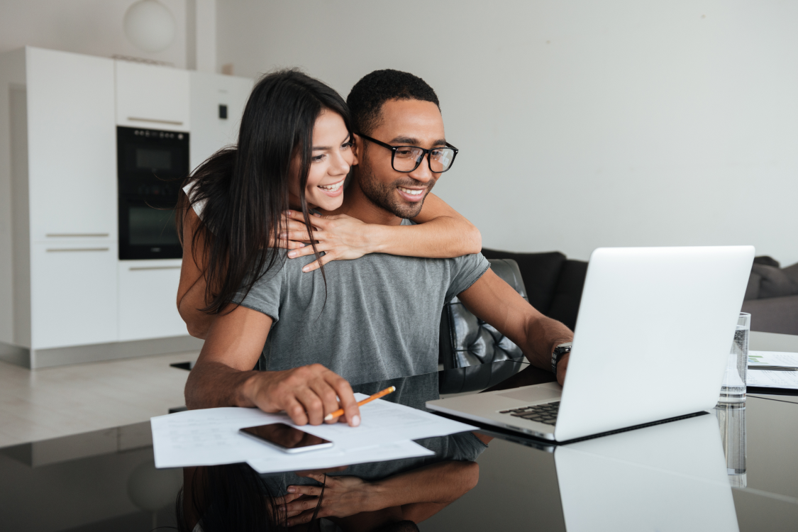 A smiling couple using a laptop together.